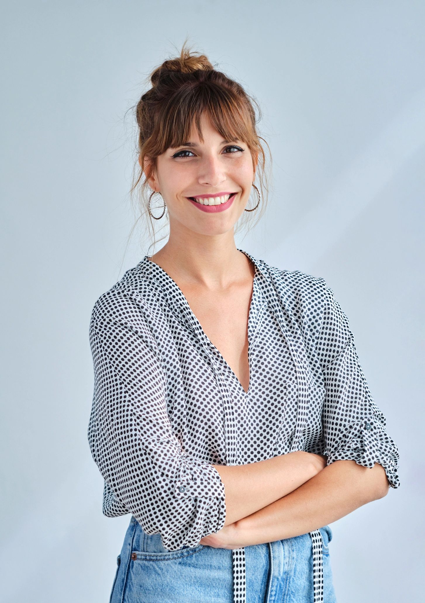 Adult woman smiling with arms crossed in a studio portrait